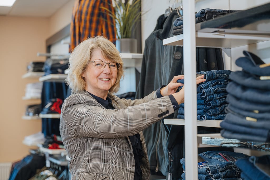 Mitarbeiterin Astrid Kamrath ordnet blaue Herrenjeans im Fachgeschäft für Grosse Grössen im Modehaus "gross-art-ich" in ein Wandregal ein.