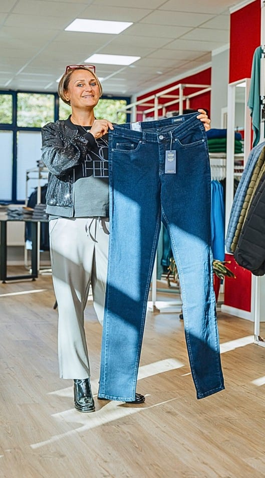 Inhaberin Anke Bahr zeigt auf, wie lang Herrenjeans im Fachgeschäft für Lange Längen im Modehaus "gross-art-ich" sein können.
